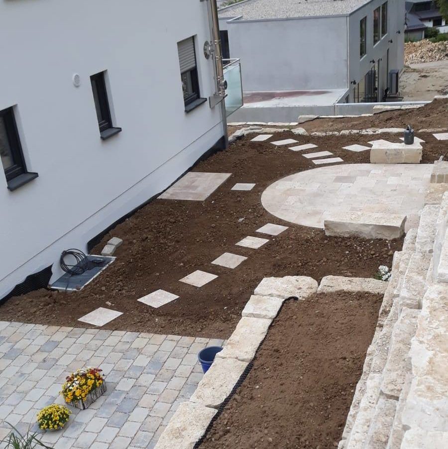 Neu gestalteter Hinterhof mit runder Steinterrasse und Stufen