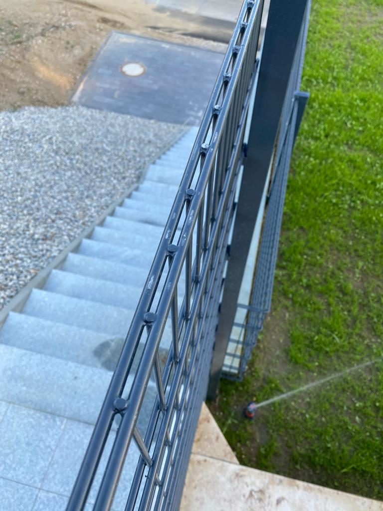 Außentreppe mit Metallgeländer von oben, hinunter zur Kiesfläche