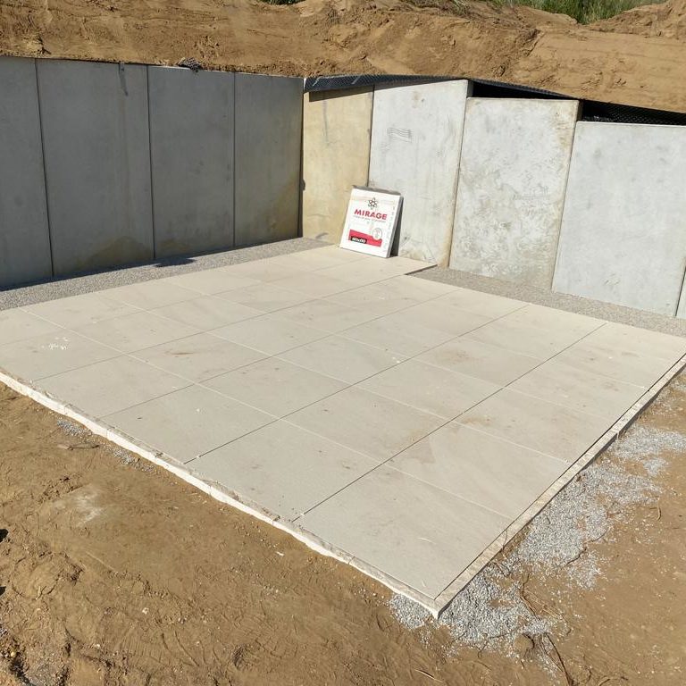 Frisch verlegte weiße Fliesen, eingefasst von Betonplatten