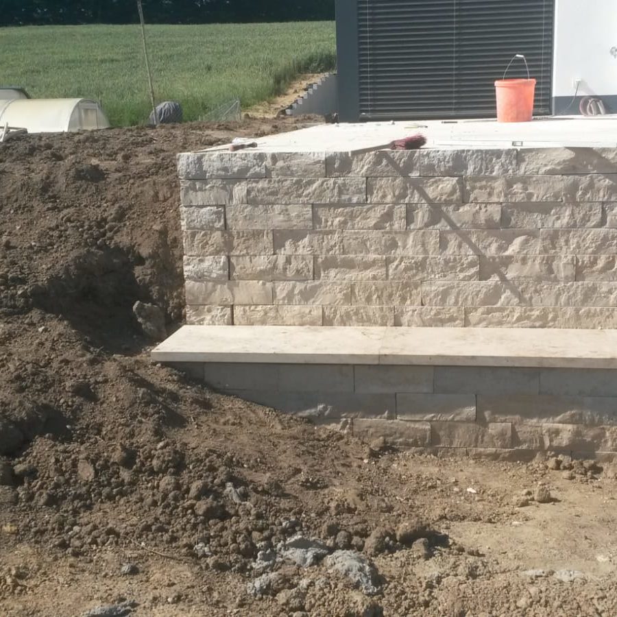 Steinmauer mit aufgeschütteter Erde auf einer Baustelle